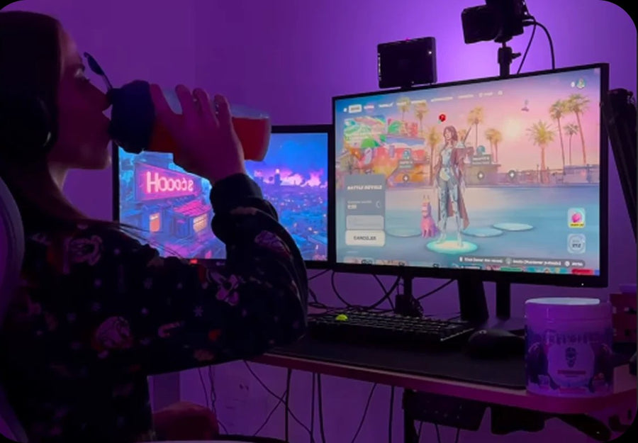 Chica jugando en su setup gaming con luz morada mientras bebe Z Drinks de un shaker, con un bote de Z Drinks en el escritorio